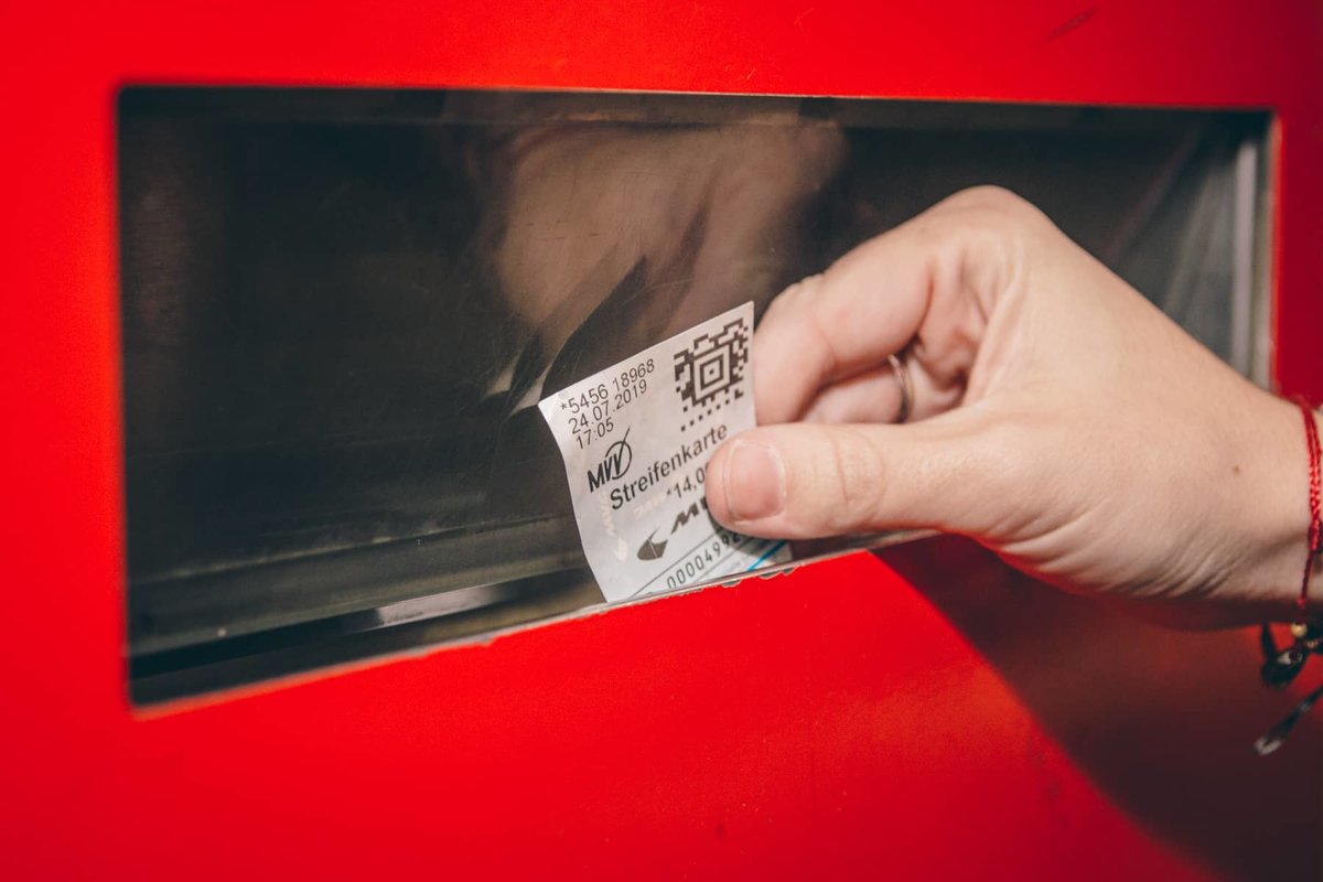 Ein Ticket wird aus dem Ausgabefach des Fahrkartenautomaten genommen