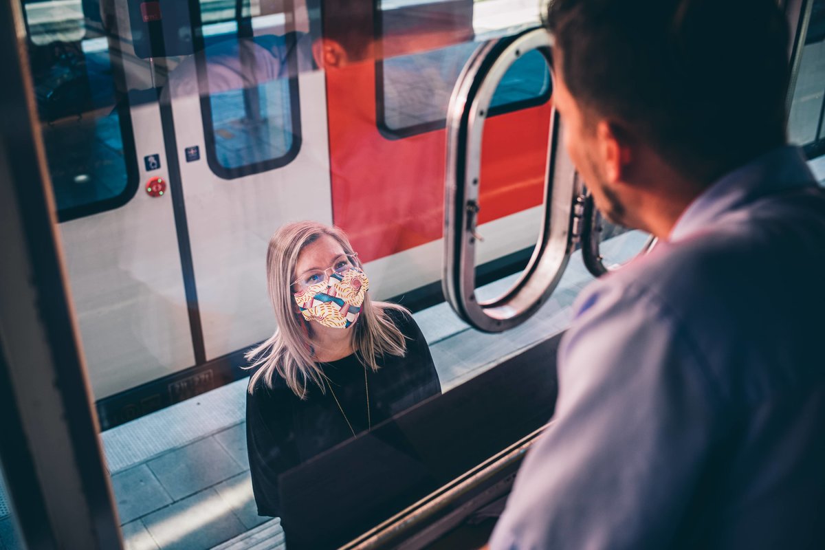 Ein Mitarbeitender der S-Bahn München spricht aus seiner Bahnsteigkanzel mit einer Frau am Bahnsteig